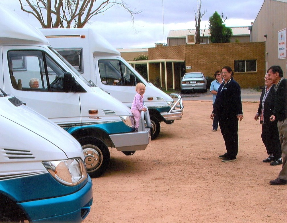 Small girl on the bumper of an old Wirraway motorhome with family onlooking